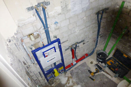 Rohinstallation eines Badezimmers mit Vorwandelement für das Wand-WC sowie neu verlegten Wasser- und Abwasserleitungen.