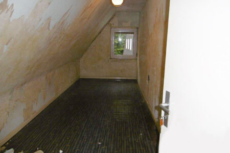 Schmaler Raum im Dachgeschoss mit Dachschräge und kleinem Fenster vor dem Umbau zu einem Badezimmer.