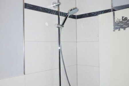 Moderne Dusche mit Regendusche, Handbrause, Thermostatarmatur und heller Wandverfliesung.
