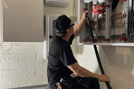 Elektriker bei der Installation und Verkabelung einer elektrischen Hauptverteilung in einem geöffneten Schaltschrank.