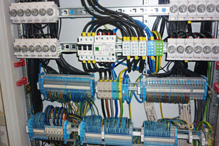 Geöffnete Elektroverteilung mit Sicherungen, Klemmleisten und übersichtlich verdrahteten elektrischen Leitungen.
