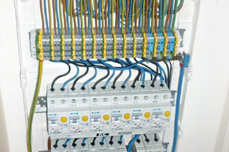 Geöffneter Sicherungskasten mit FI-Schutzschaltern, Leitungsschutzschaltern und sauber verdrahteten elektrischen Leitungen.