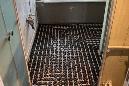 Verlegte Heizrohre einer Fußbodenheizung auf Noppenplatten während der Sanierung eines Badezimmers.