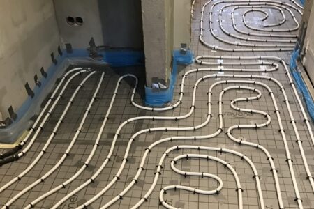 Flächig verlegte Heizrohre einer Fußbodenheizung auf Dämmplatten in mehreren Räumen während der Sanierung.