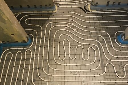 Detailansicht der verlegten Heizrohre einer Fußbodenheizung auf Dämmplatten während der Installation.