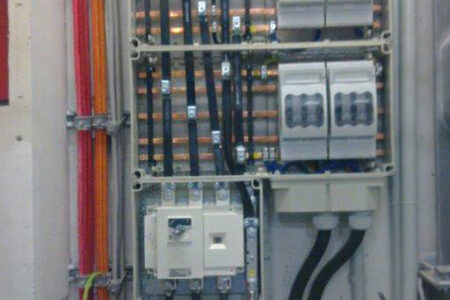 Geöffneter Schaltschrank einer elektrischen Hauptverteilung mit Sicherungen, Stromschienen und Starkstromleitungen.