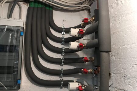 Heizkreisverteiler mit mehreren gedämmten Rohrleitungen, Absperrventilen und elektrischen Stellantrieben.