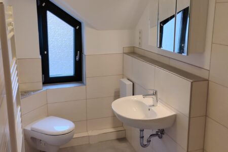 Modernes Badezimmer im Dachgeschoss mit Badewanne, Waschtisch, Wand-WC und Handtuchheizkörper.