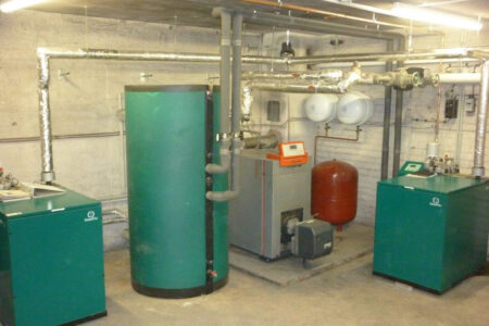 Heizungsraum mit zwei SenerTec Dachs Blockheizkraftwerken, Heizkessel, Pufferspeichern und gedämmten Rohrleitungen.