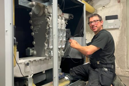 Techniker bei Installationsarbeiten an einem geöffneten SenerTec Dachs Blockheizkraftwerk im Heizungsraum.