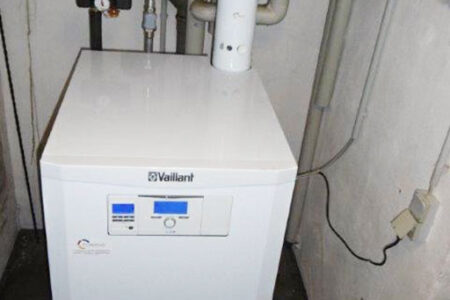 Modernisierte Vaillant-Gasheizung mit angeschlossenen Heizungsrohren und Regelung in einem kleinen Heizungsraum.