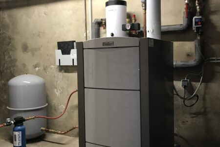 Moderner Vaillant-Heizkessel mit Rohrleitungen, Umwälzpumpe und Ausdehnungsgefäß in einem Kellerraum.