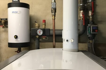 Moderne Vaillant-Heizungsanlage mit Warmwasserspeicher, Rohrleitungen, Umwälzpumpe und Armaturen im Heizungsraum.
